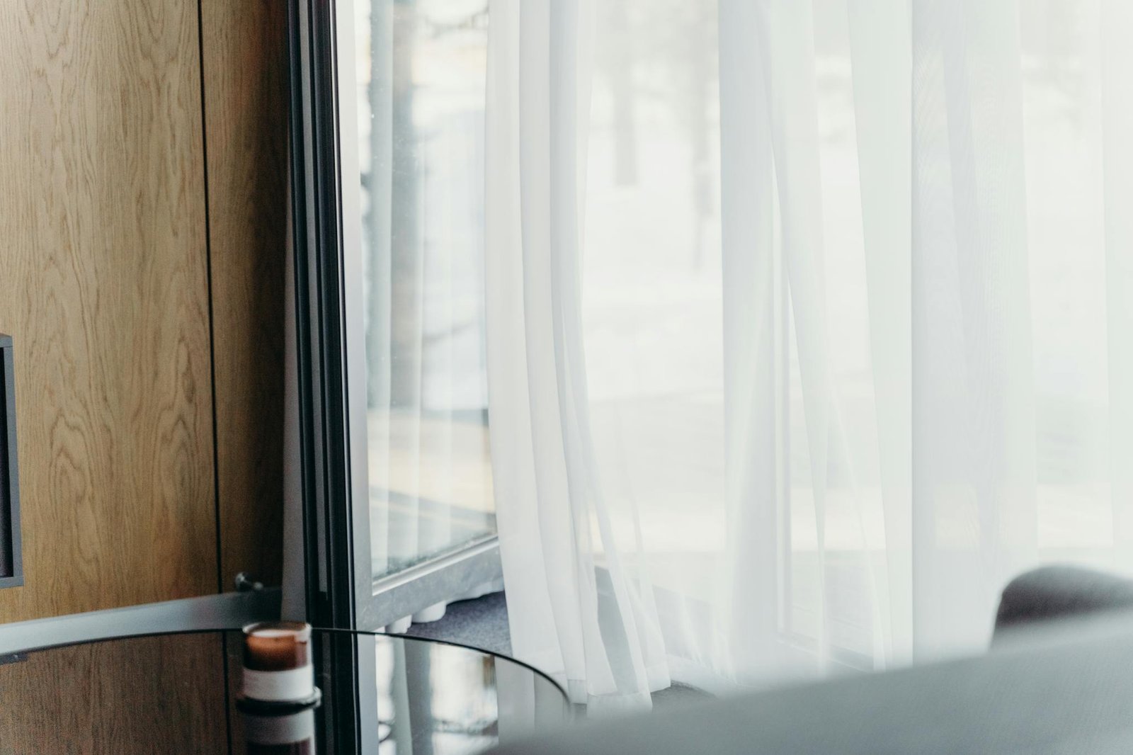 A modern hotel room with sheer curtains softly lit, emphasizing luxury and tranquility.